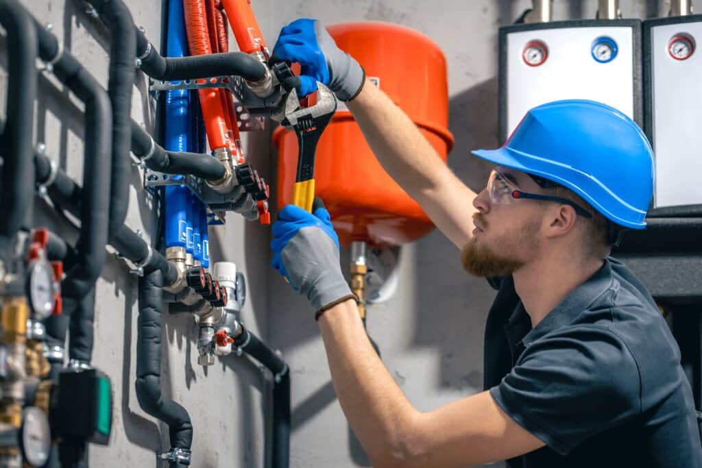 A commercial plumber in Brisbane performing pipe installation and system adjustments in a mechanical plant